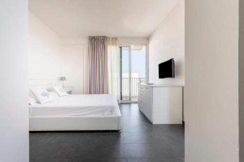 a white bedroom with a bed and a television at Case Vacanze Otranto in Otranto