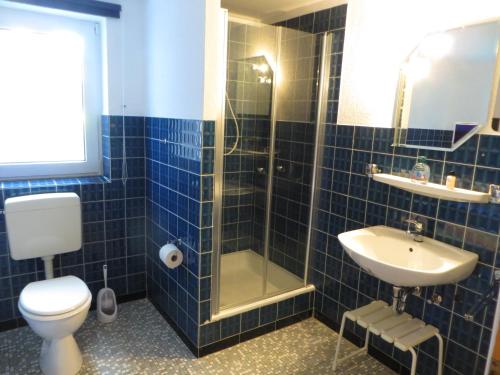a blue tiled bathroom with a toilet and a sink at Waldblick in Gellersen