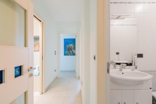 a white bathroom with a sink and a hallway at Dimora di Artemide in Otranto