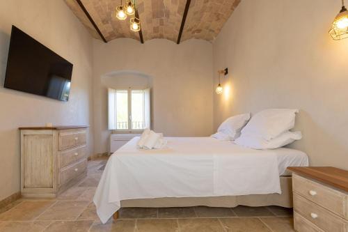 a bedroom with a white bed and a television at Borgo Ariano near Volterra by PosarelliVillas in Volterra