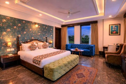 a bedroom with a large bed and a blue chair at The Colonial - A Lake View Hotel in Udaipur in Udaipur