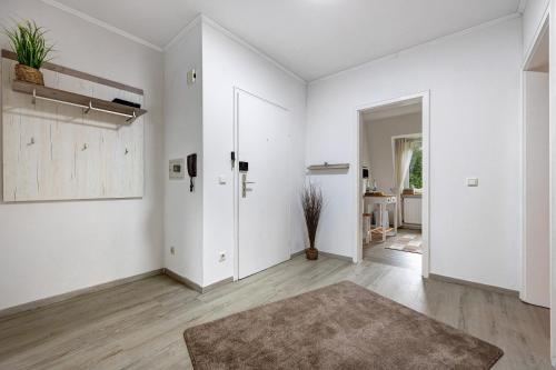 an empty living room with white walls and wooden floors at Ferienwohnung Berti in Heeßen