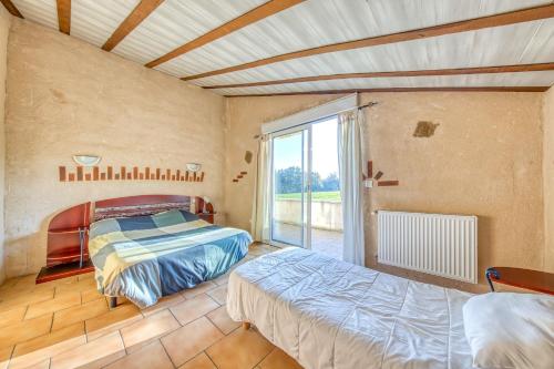 a bedroom with two beds and a large window at L'Ecurie in Guizengeard