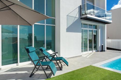 a group of chairs sitting on a patio next to a swimming pool at Pico Do Paraíso in Funchal