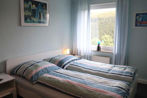 a bed with striped sheets in a bedroom with a window at Ferienwohnung Voege am Waldrand in Schmallenberg