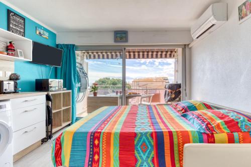 a bedroom with a colorful bed and a balcony at Les Ptits Loups, le Grau d'Agde in Le Grau-dʼAgde
