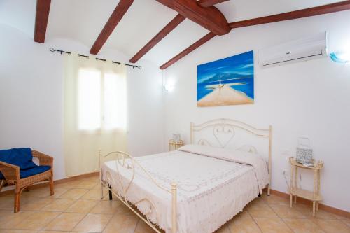 a bedroom with a white bed and a chair at Villa Funtana Cortese in Orosei