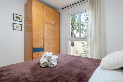 a bedroom with towels on a bed with a window at Dorada Apartment Lluna in Calafell