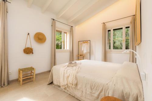 a white bedroom with a bed and two windows at Es Pinaró Sansó in Artá