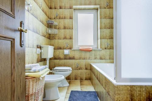 a bathroom with a toilet and a tub and a sink at Ciasa Christina in Moena