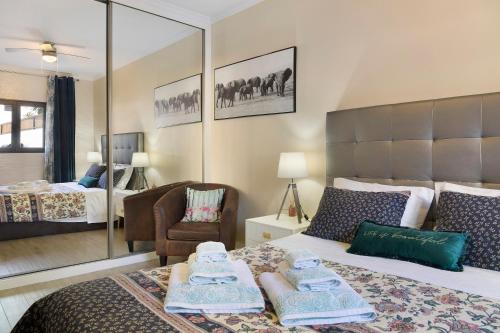 a bedroom with a bed and a chair and a mirror at Villa Garajau House in Caniço