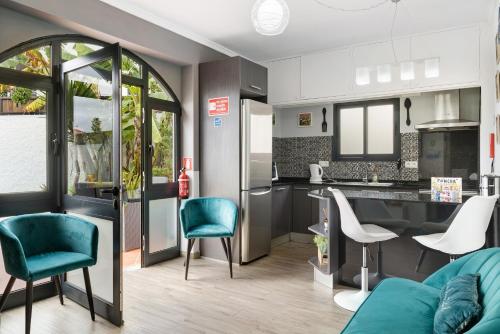 a kitchen and living room with a couch and chairs at Villa Garajau House in Caniço