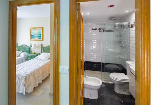 a bathroom with a shower and a toilet and a bed at La Reserva de Alvarito in Marbella