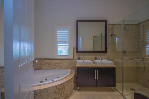 a bathroom with a tub and two sinks and a shower at 8 Tinderwood Lane in Ballito