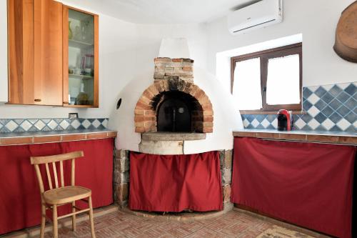 a kitchen with a brick oven with red curtains at Casa Ami in Arzana