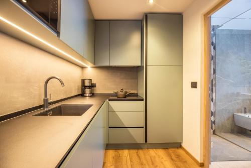a kitchen with white cabinets and a sink at Apartments Armeri Blue Dolomites in San Vigilio Di Marebbe