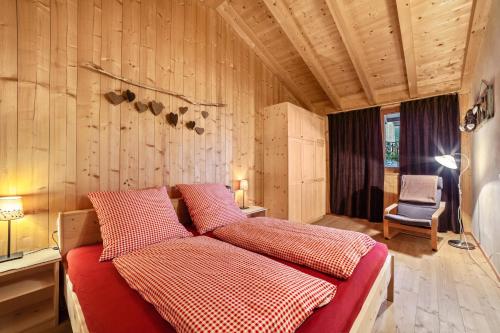 a bedroom with a bed with red sheets and a chair at Grushof App Köpfl in Sluderno