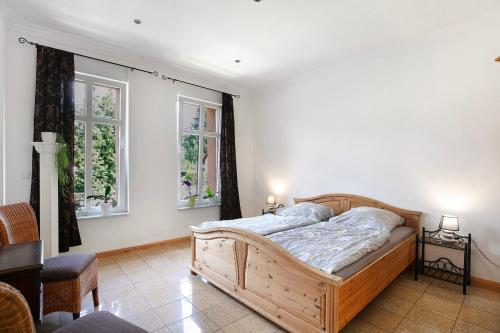 a bedroom with a wooden bed and two windows at Ferienwohnung Bestensee in Bestensee