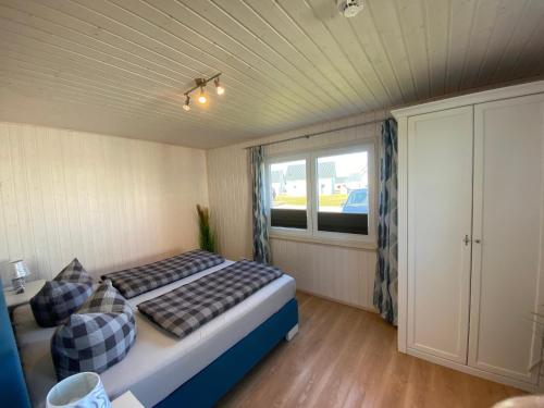 a small bedroom with a bed and a window at Skipper Hus by Seeblick Ferien in Olpenitz