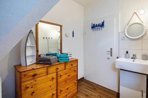 a bathroom with a sink and a wooden dresser with a mirror at Haus am Vogelsang in Hannoversch Münden