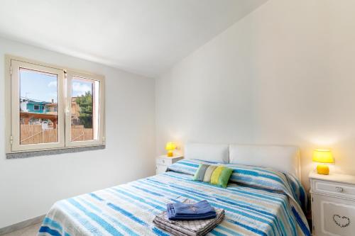 ein weißes Schlafzimmer mit einem Bett und einem Fenster in der Unterkunft Casa Angus in Badesi