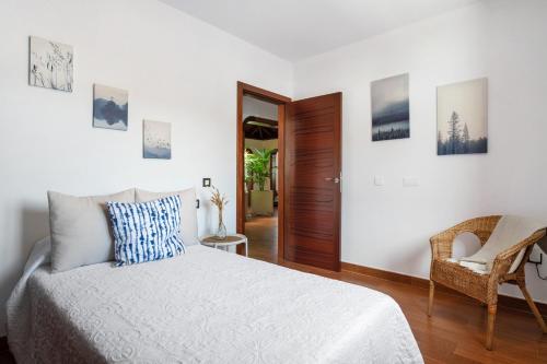 a white bedroom with a bed and a chair at Villa Tahoyo in Máguez