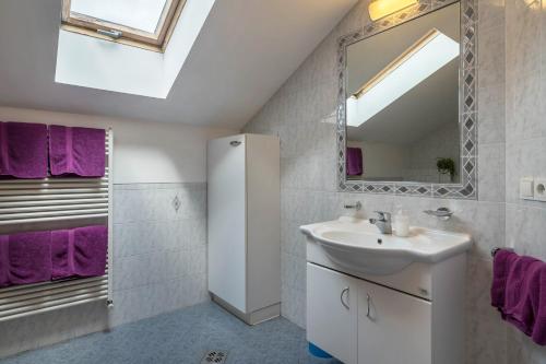 a bathroom with a sink and a mirror and purple towels at Woehrmannhof Apt Birnblüte in Feldthurns