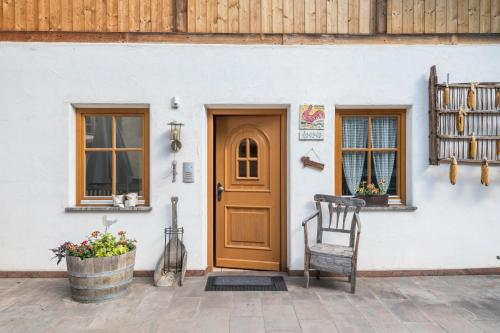 a house with a wooden door and a chair at Woehrmannhof Apt Birnblüte in Feldthurns