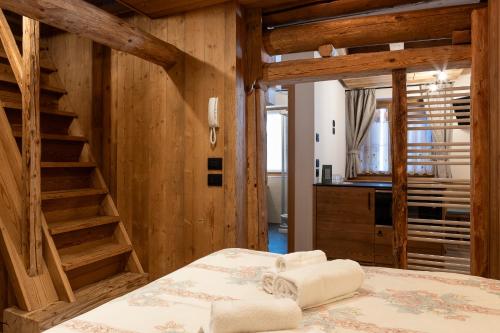 a bedroom with a bed with wooden walls and a staircase at Alpine Mood Apartments in Falcade