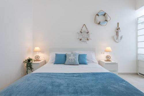 a white bedroom with a large bed with blue pillows at La casa dei naviganti in Villasimius