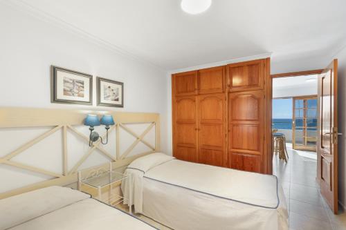 a bedroom with two beds and a door to the ocean at Playa Delphin 306 in Puerto Naos