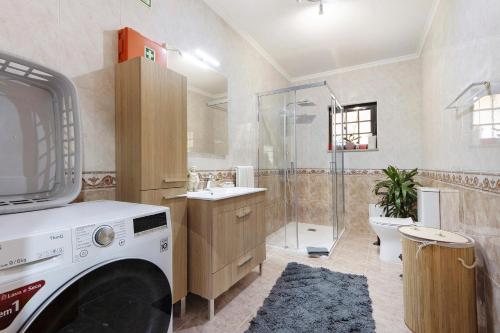 a washing machine in a bathroom with a shower at Casa De Santo Amaro in Carrazedo