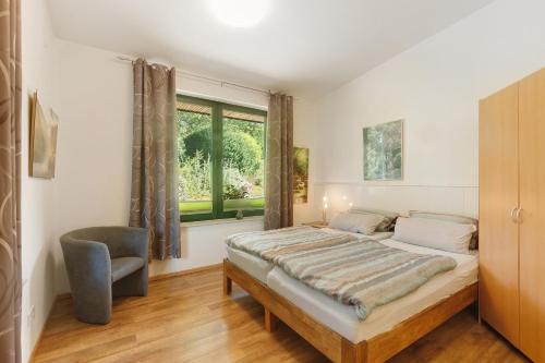 a bedroom with a bed and a chair and a window at Ferien im Grünen in Mammelzen