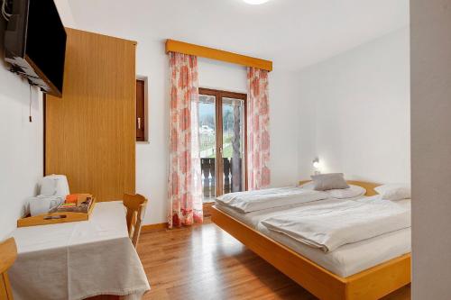 a bedroom with two beds and a tv and a window at Harmony room in Piano