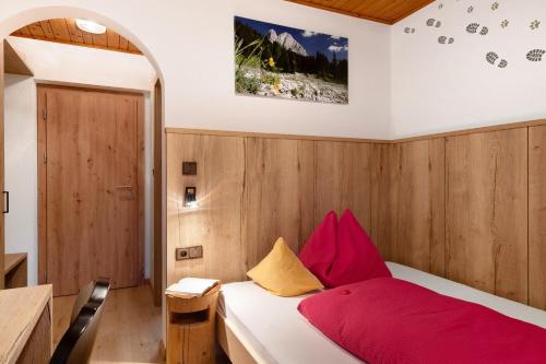 a bedroom with a bed with red and yellow pillows at Stampferhof in Völs am Schlern