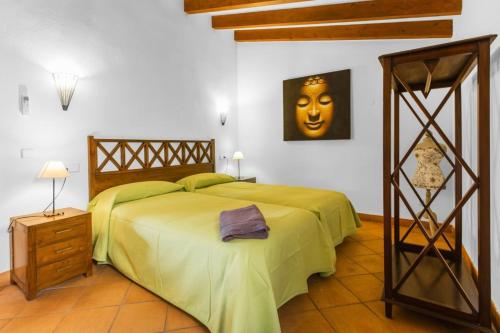 a bedroom with a large bed with a green blanket at Es Tarongers in Sóller