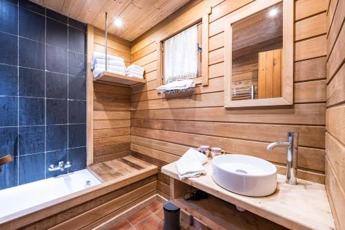 a bathroom with wooden walls and a sink and a tub at Chalet Farapreu in Manigod