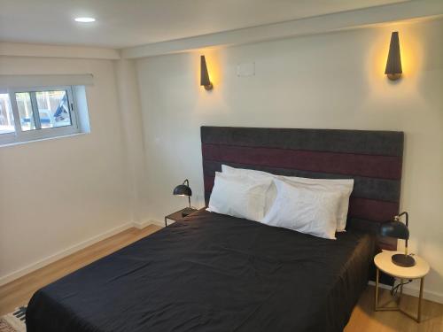 a bedroom with a bed with a black blanket and white pillows at Maia House da Piscina in Folgosa