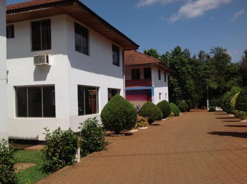 a white building with a brick walkway in front of it at Keys Hotel Mbokomu Branch in Moshi