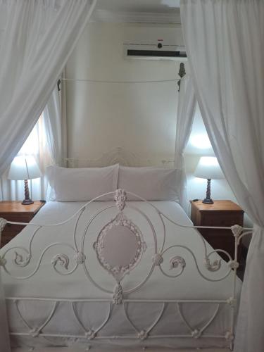 a bedroom with a white bed with two lamps at De Kothuize 10 in Graaff-Reinet