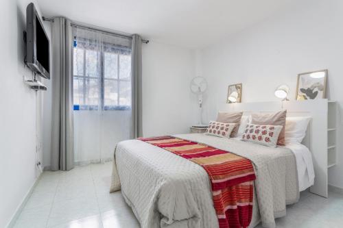 a white bedroom with a bed and a television at Retama in Adeje