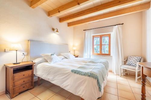 a bedroom with a large white bed and a chair at Es Lledoner 2 in Islas Baleares