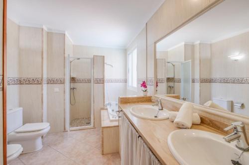 a bathroom with two sinks and a toilet and a mirror at Villa Loli in Alcudia