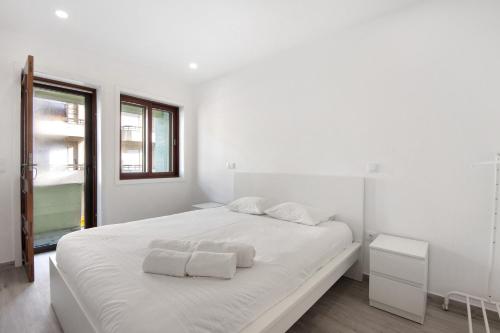 a white bedroom with a large bed with towels on it at T4 Furadouro with sea view in Ovar