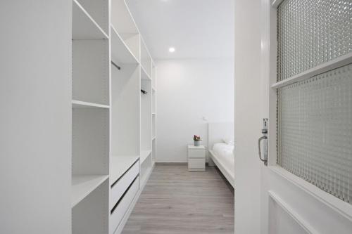 a hallway leading to a bedroom with white walls and wood floors at T4 Furadouro with sea view in Ovar