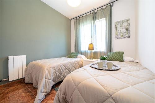 two beds in a room with a table and a window at another day in paradise in Calafell