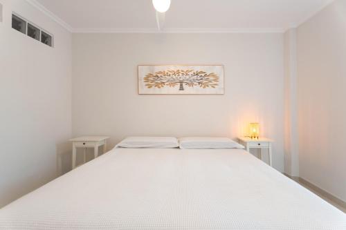 a white bedroom with a large white bed with two tables at Ático Bellavista B - Alcalá in Guía de Isora