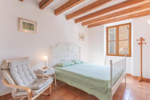 a bedroom with a bed and a chair and a window at Cas Pobres in Sóller
