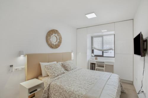 a white bedroom with a bed and a television at Sun and serenity pool wifi in Puerto Rico de Gran Canaria