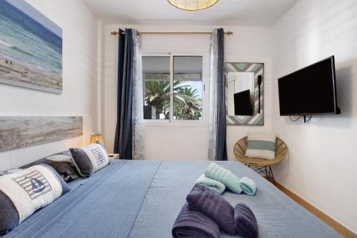 a bedroom with a bed with a tv on the wall at Casa Verdemar in Corralejo